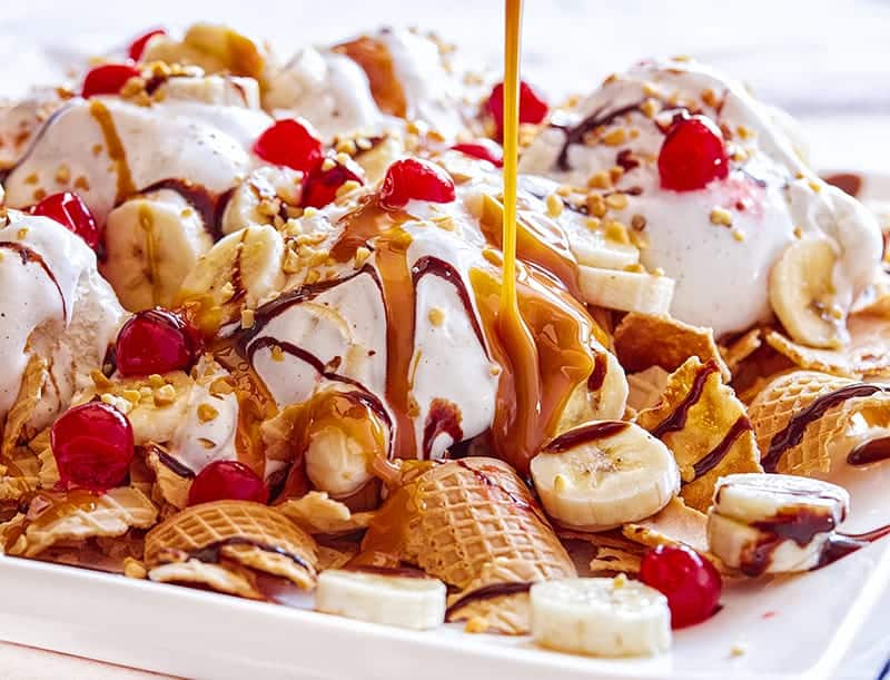 Top the waffle cone pieces with ice cream, bananas, cherries, caramel, chocolate and nuts to create these Banana Split Nachos! #bananasplitnachos #bananasplit #iambaker #wafflecone #icecream #nachos #dessertnachos #recipes #desserts #icecream Banana Split Nachos