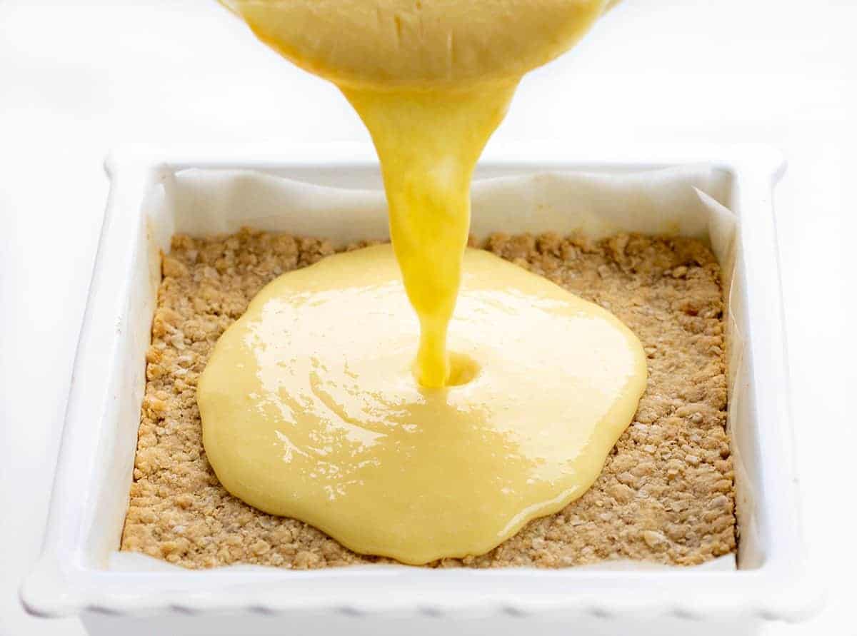 Lemon Crumb Bars are dessert bars filled with lemon filling and flavor in between two layers of an oatmeal crust. They are one of the BEST lemon desserts I have ever had! Lemon Bars, Lemon Crumble, Lemon Crumb Bars, Best Lemon Desserts, Dessert, Summer Dessert, Spring Dessert, Easy Dessert, Crowd Pleasing Dessert, Crumble Dessert, recipes, baking, i am baker, iambaker Adding Lemon Filling to Lemon Crumb Bars