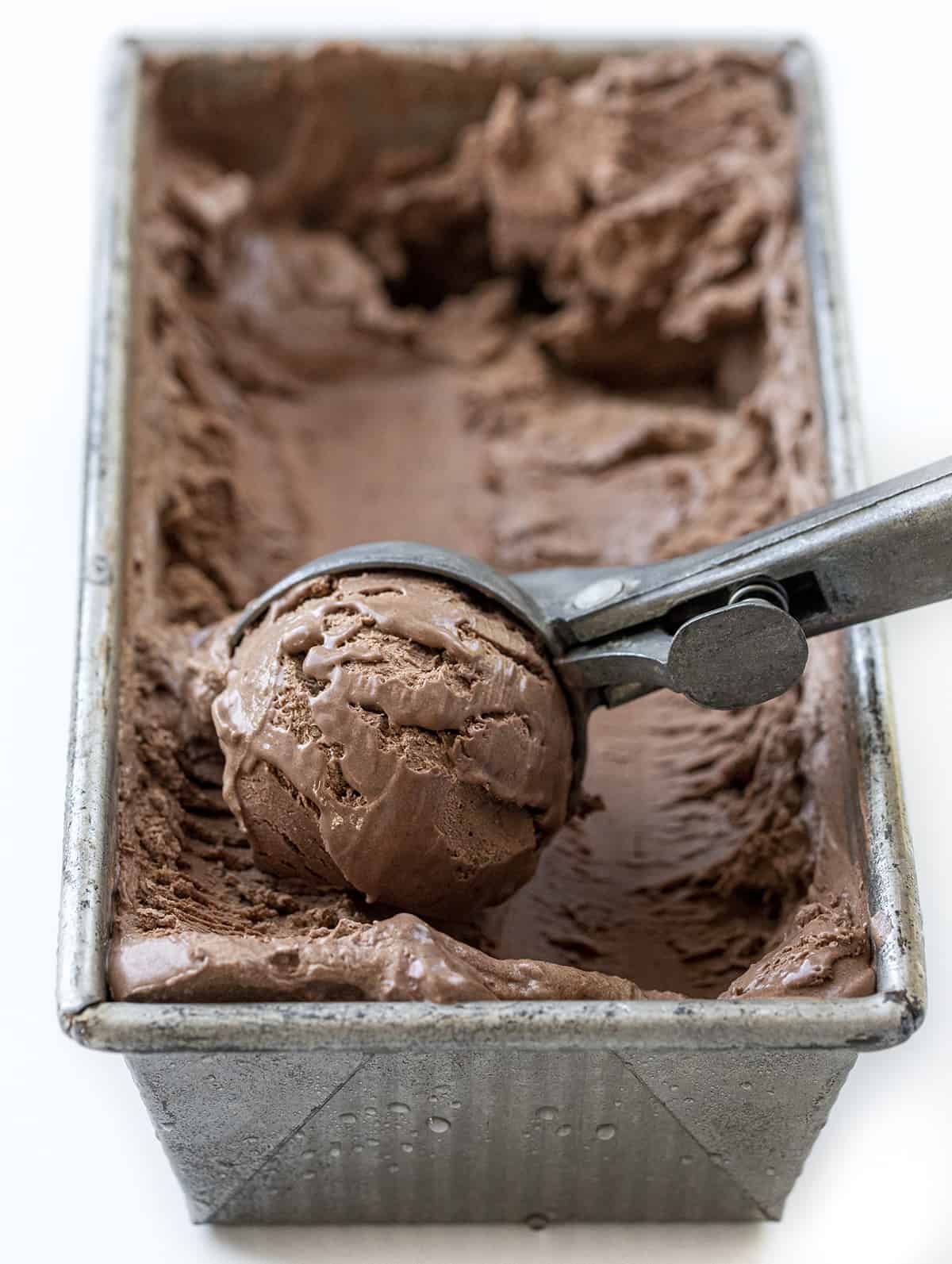 Pan with a Scoop of no-Churn Chocolate Ice Cream in the Front Showing Texture.