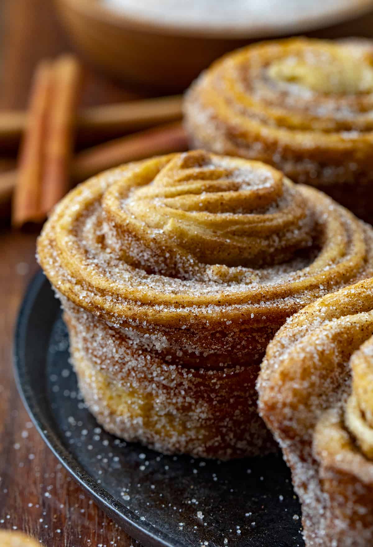 Close up of a Cruffin on a Black Platter. Baking, Breakfast, Cruffins, Croissant Muffins, Easy Cruffins, Easy Cruffin Recipe, Fall Baking, Cinnamon Cruffins, Cinnamon Sugar Cruffins, Dessert, Breakfast Ideas, Brunch Recipes, i am baker, iambaker