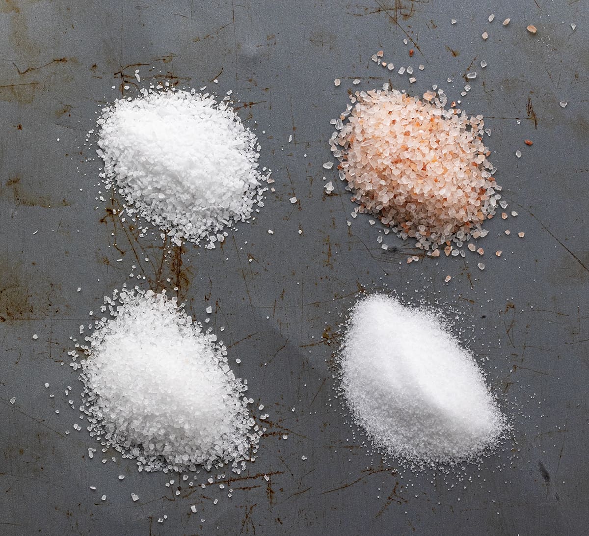 I often get asked about the role of salt in baking, especially kosher as that is what I prefer. Salt is not just a flavor enhancer, but it also plays a vital role in the baking process. In fact, it's one of the four essential ingredients in bread - flour, salt, yeast, and water. I'd love to share which salt I use, and why different salts can't be used interchangeably! Showing Four Different Salts, Table Salt, Sea Salt, Kosher Salt, and Himalayan Salt.