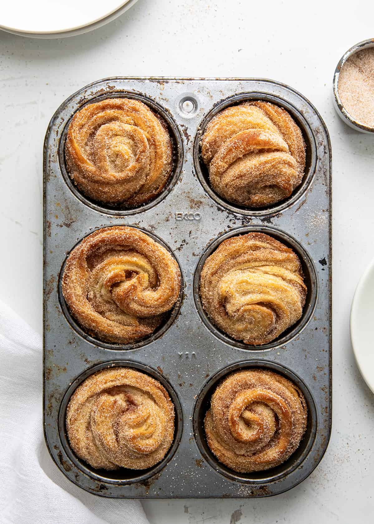 Made entirely from scratch, Homemade Cruffins (croissant + muffin) have buttery, flaky layers with a cinnamon-sugar filling, baked to golden perfection. They are a delightful treat with your morning cup of coffee or tea. Or, enjoy one as a snack or as a dessert! Pan of Homemade Cruffins, Made with a Croissant Dough into Muffin Shapes.