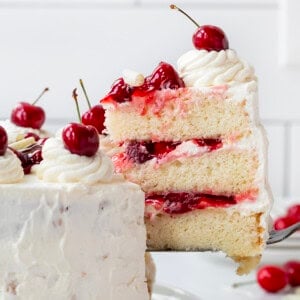 Cake server picking up a piece of White Forest Cake from cake plate.