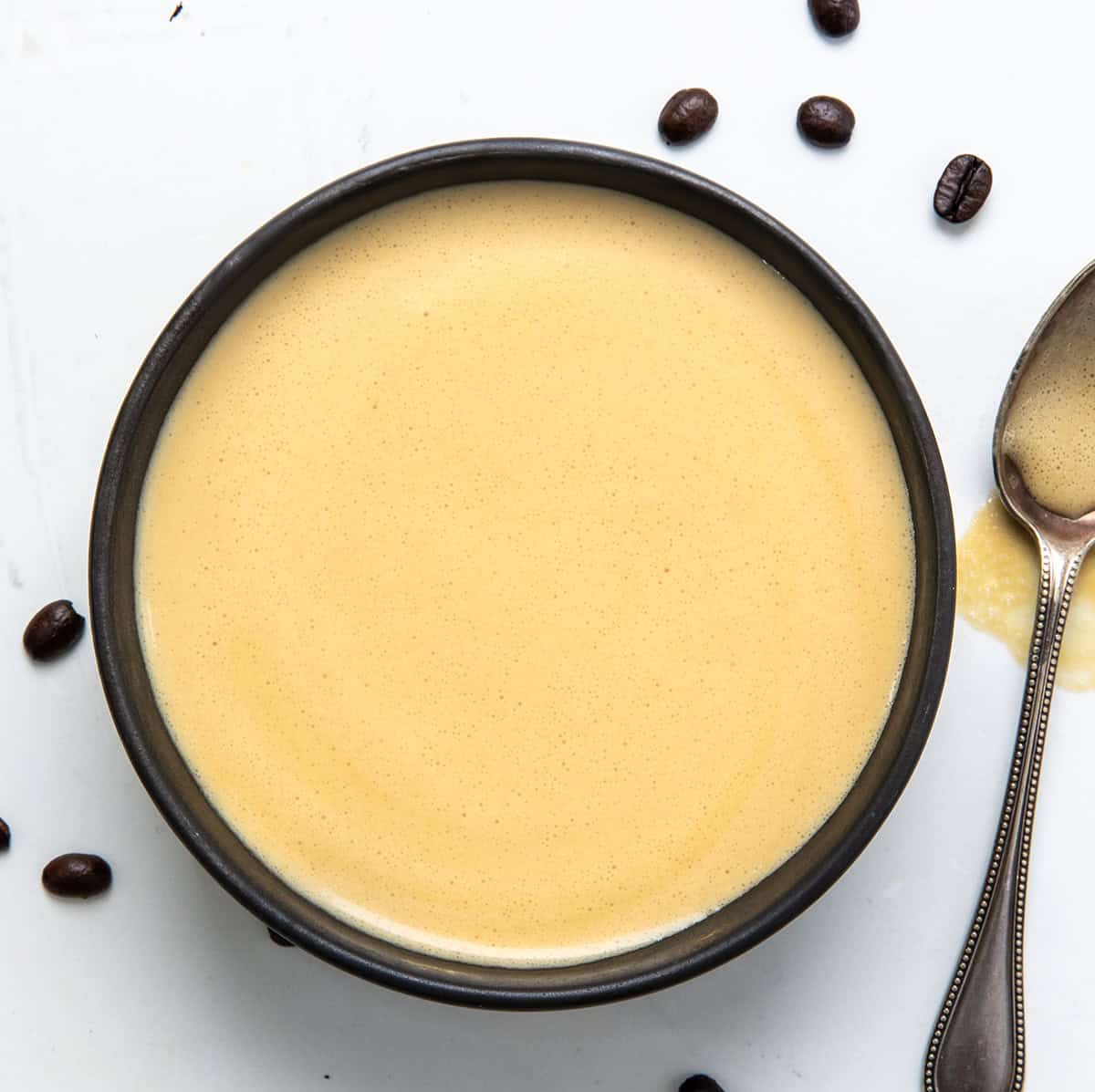 This Coffee Sauce is creamy and smooth, has rich coffee flavor, and the perfect amount of sweetness! Bowl of Coffee Sauce on a white table from overhead.