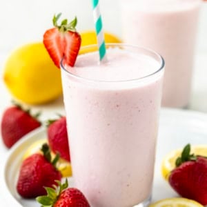 Glasses of Frosted Strawberry Lemonade on a white platter with strawberries and lemons.